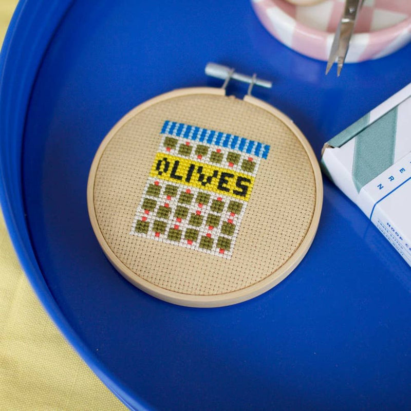 Cross-stitched hoop with 'OLIVES' text on a blue tray
