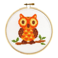 Cross-stitched owl design in a wooden hoop on a white background
