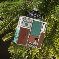 Decorative ornament resembling a vintage photo booth on a Christmas tree.