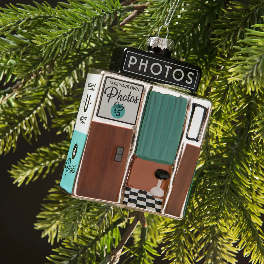 Decorative ornament resembling a vintage photo booth on a Christmas tree.