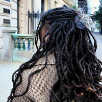 Person with dreadlocks wearing a pigeon-shaped claw clip.