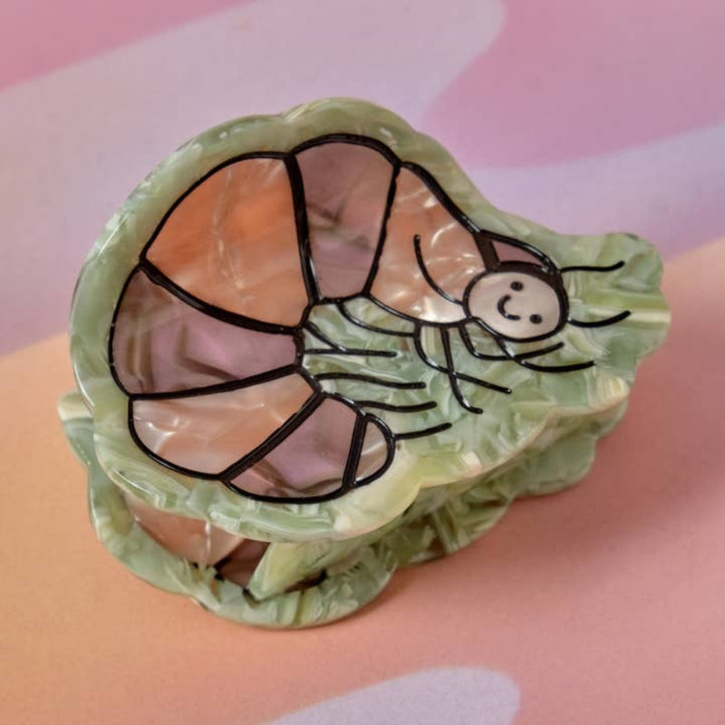 Shell with a painted pillbug design on a pink background