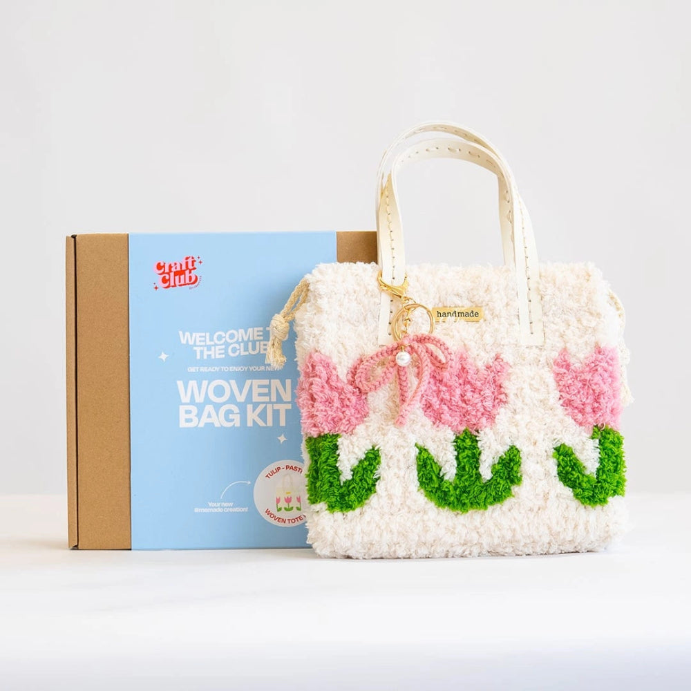 A fluffy pink tulip with green stem designed purse with a pink bow keychain rests against a box with the label "Woven Bag Kit".