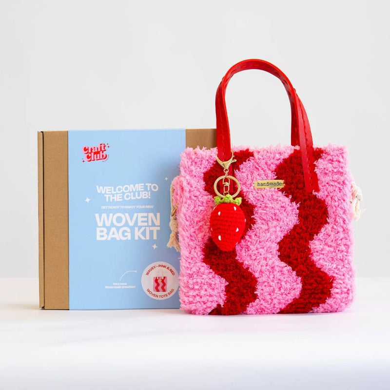 A fluffy pink and red wavy design purse with a strawberry keychain rests against a box with the label "Woven Bag Kit".