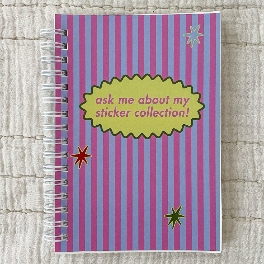 A pink and blue striped notebook titled "ask me about my sticker collection!" on a beige background.
