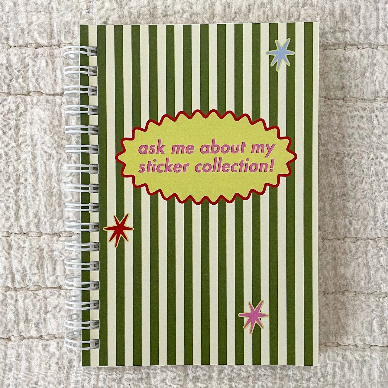 A green and white striped notebook titled "ask me about my sticker collection!" on a beige background.