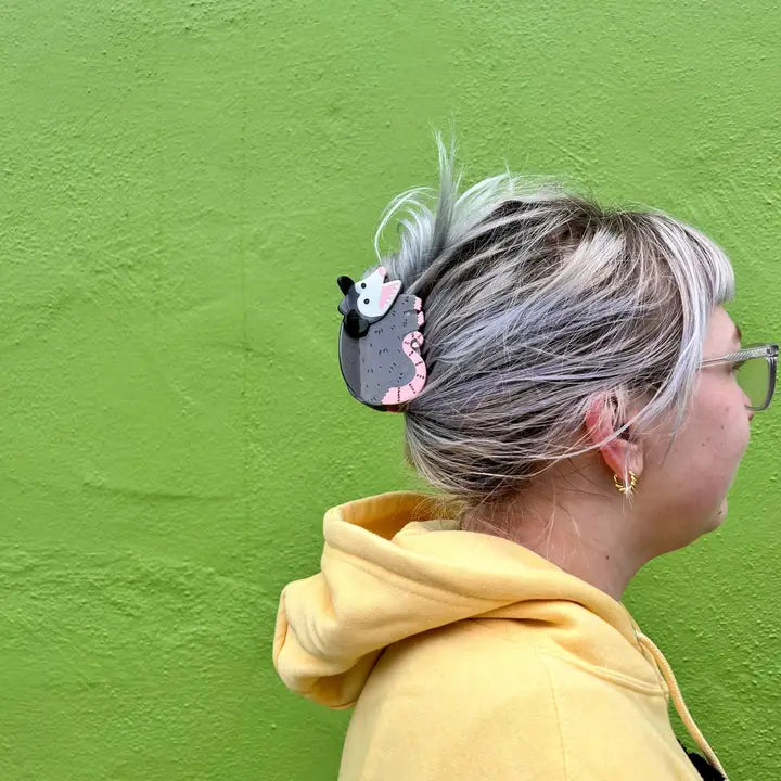 Person with a possum hair clip against a green wall