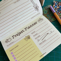 Project planner notebook with sewing-themed design on a green cutting mat.