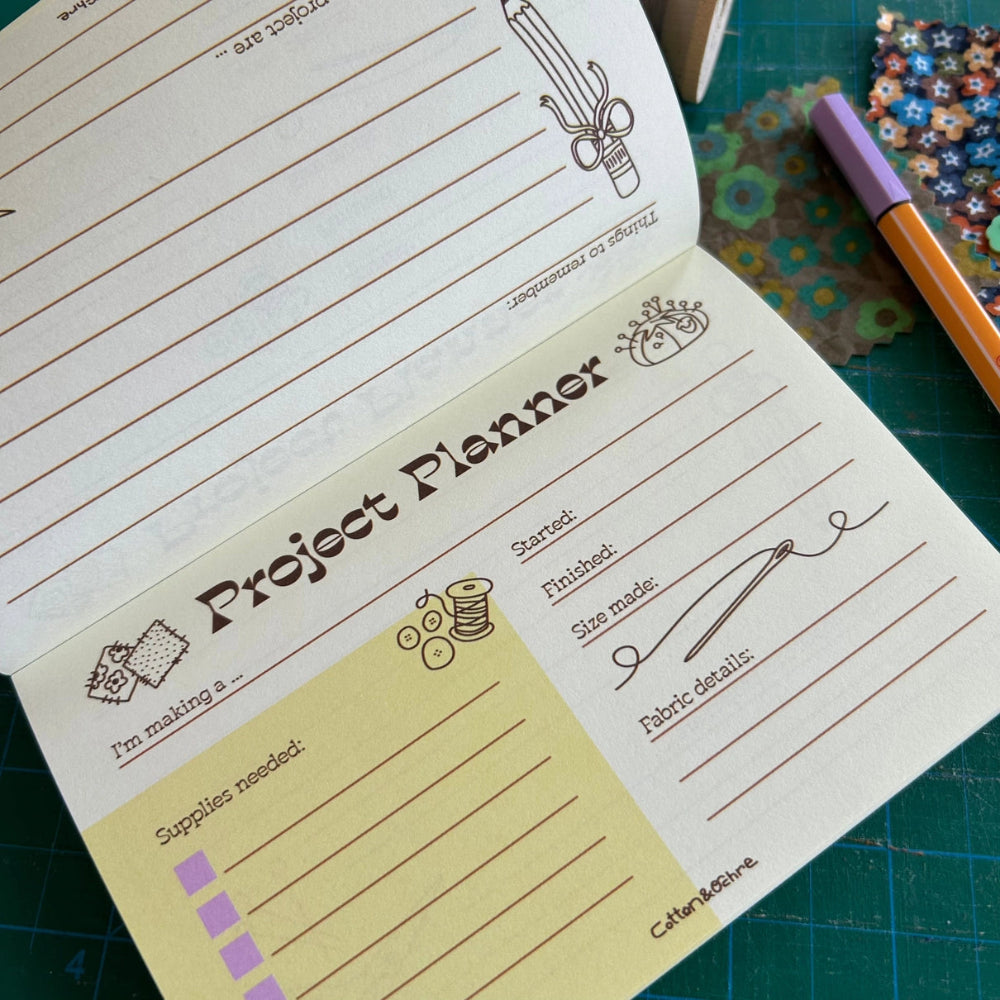 Project planner notebook with sewing-themed design on a green cutting mat.