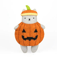 A felt cat toy dressed in a pumpkin costume, featuring a gray body, an orange pumpkin-shaped outfit with black embroidered facial features, and a striped orange and yellow pumpkin hat with a green stem, set against a plain white background.