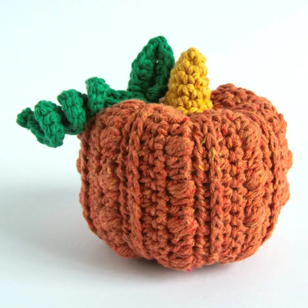 A colorful crochet pumpkin with a curling stem against a white background.