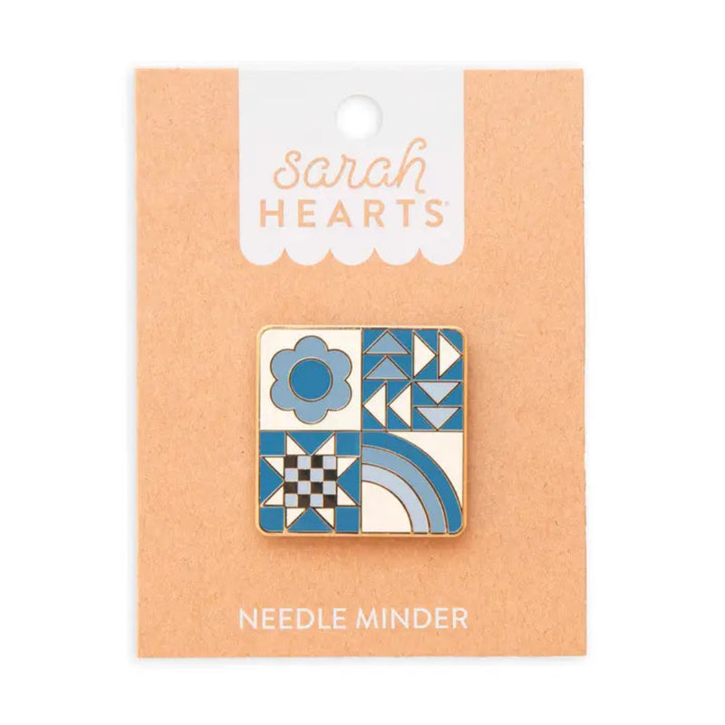 Square needle minder with different designs: blue flower, a quilting star, triangles, and a rainbow on brown backing labeled "Sarah Hearts"