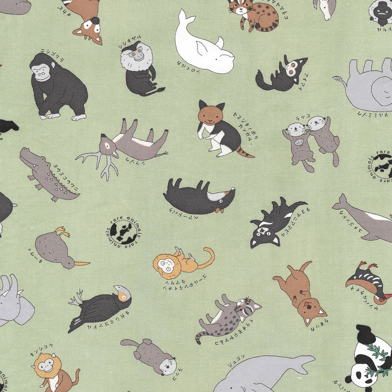 Close up of a green patterned fabric featuring illustrations of various animals including gorillas, deer, monkeys, otters, and birds, each with small Japanese text above them.