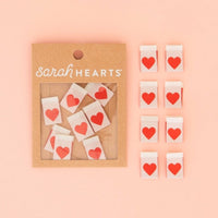 Packaging of 'sarah HEARTS' with heart-shaped labels on a pink background