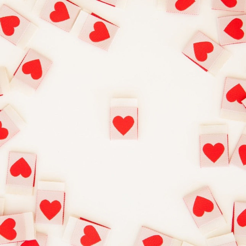 Labels with red heart symbols arranged in a pattern on a white background