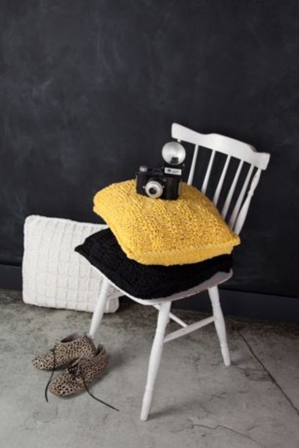 Yellow cushion with a camera on a white chair against a dark background