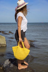 Woman holding a yellow bag by the water