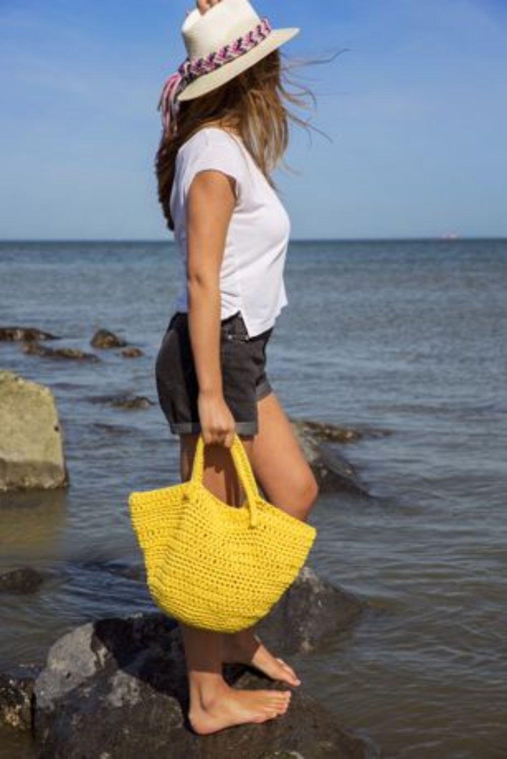 Woman holding a yellow bag by the water