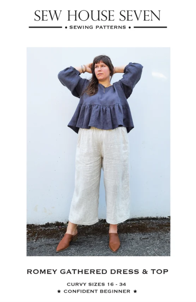 Plus size model wearing cream linen pants and a navy baby doll top with brown shoes on a white background with Sew House Seven branding.