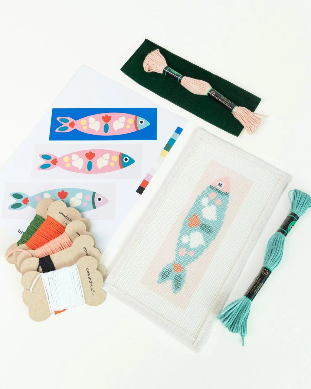 Needlepoint canvas, pattern, and thread against a white background