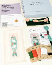 Needlepoint kit with materials and instructions on a white background