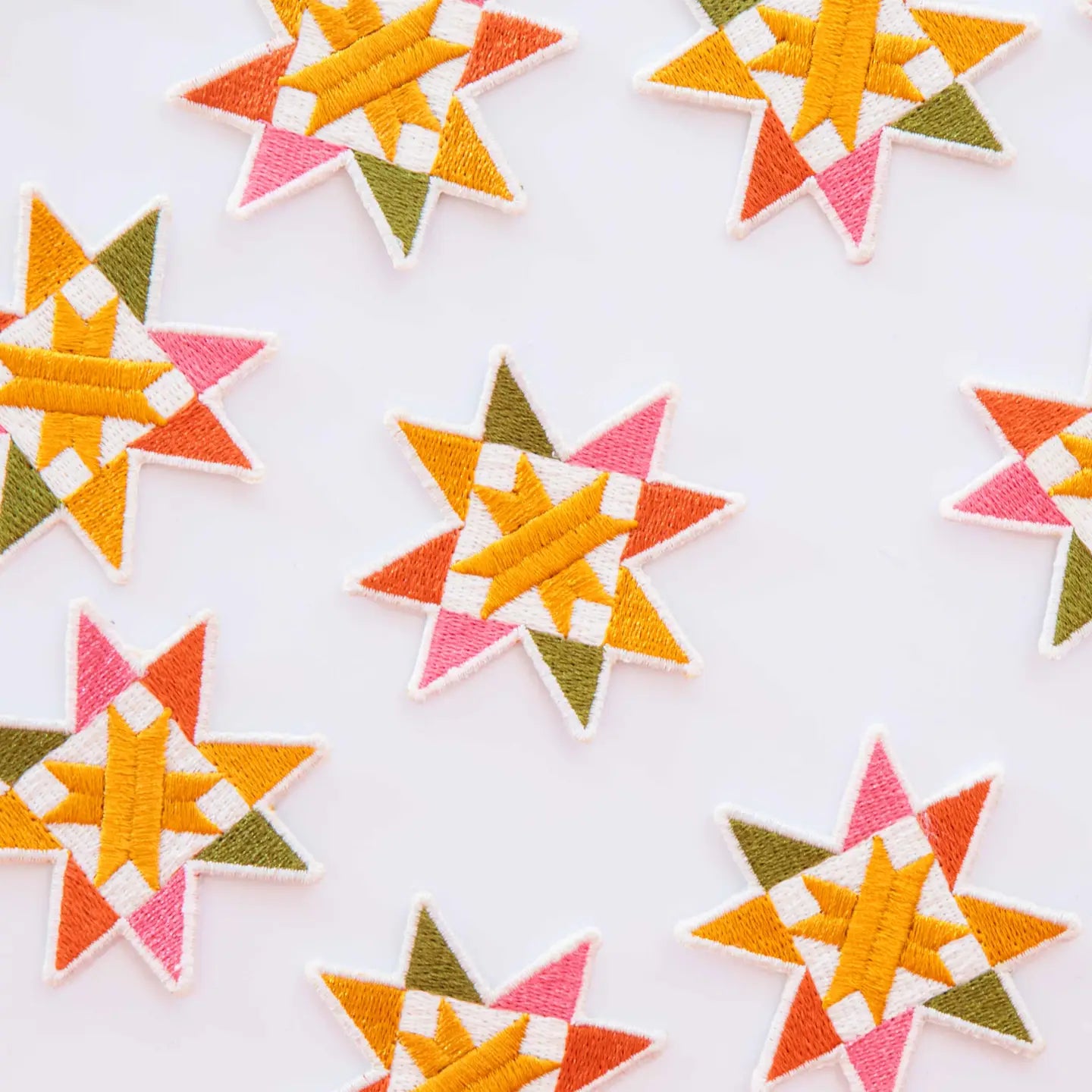 Colorful iron-on patches in the shape of a sawtooth quilt block on a white background