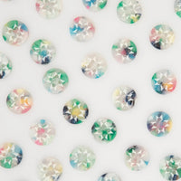 A close-up arrangement of small round iridescent buttons with star-shaped print, scattered on a plain white background.