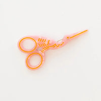 A translucent pink stork scissors with gold accents set against a plain white background.