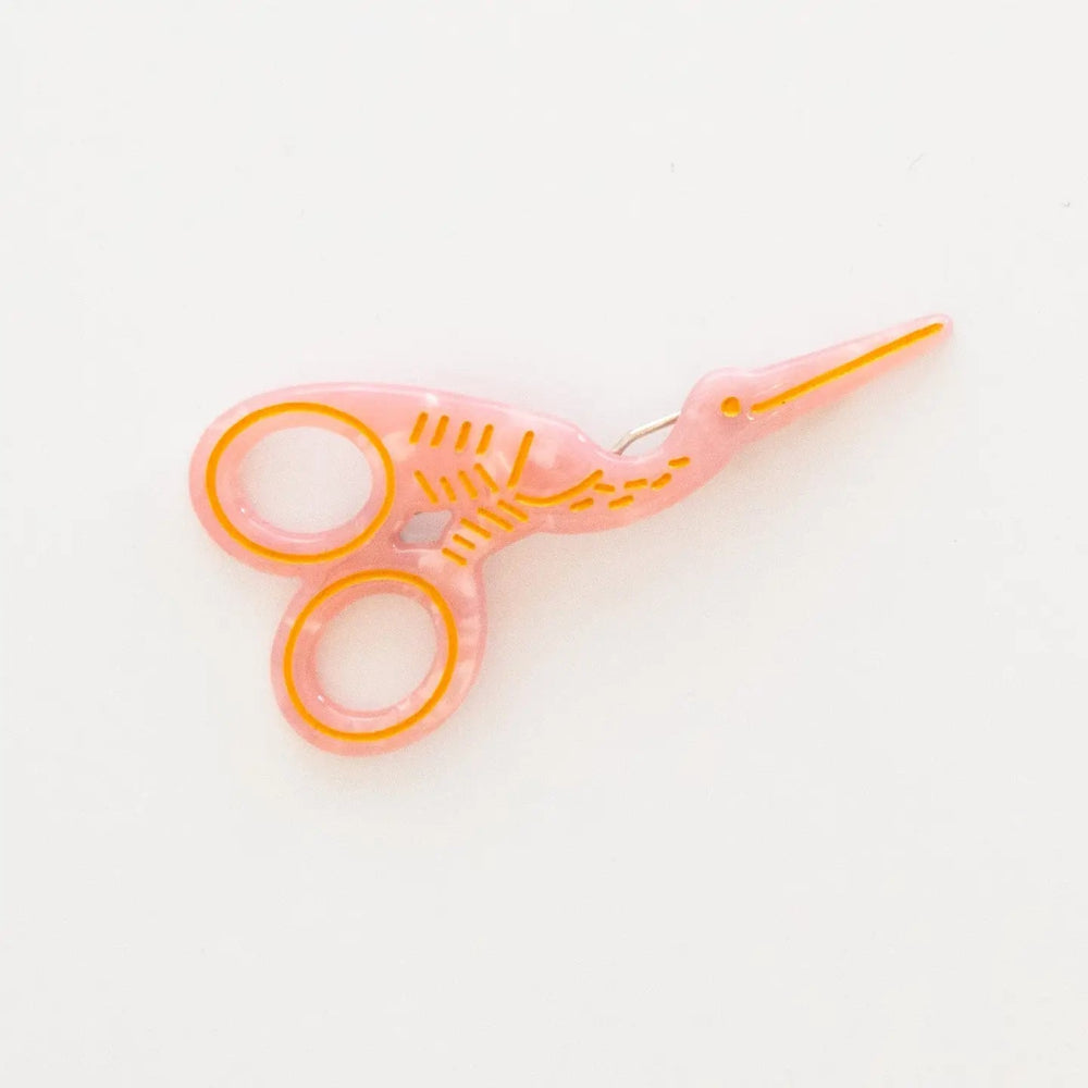 A translucent pink stork scissors with gold accents set against a plain white background.