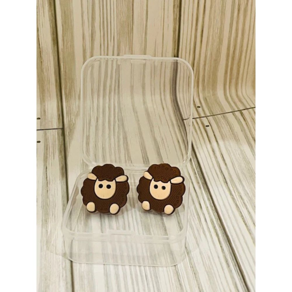 Sheep-shaped knitting needle point protectors on a clear stand against a wooden background