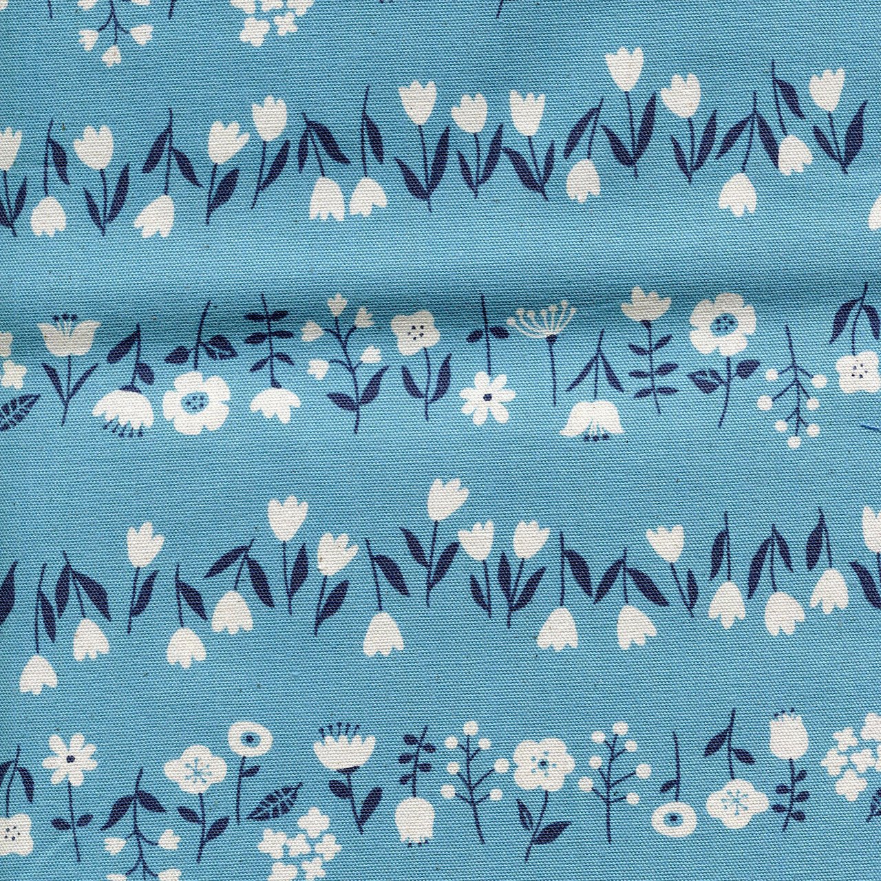 Patterned fabric featuring white flowers with dark blue stems and leaves on a light blue background