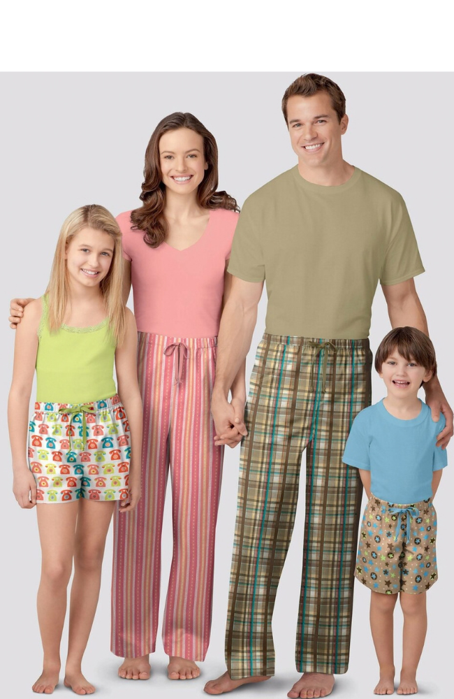 A family of four modeling matching pajama sets against a light gray studio background. 