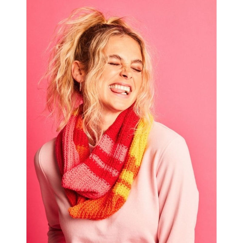 Person wearing a colorful scarf against a pink background
