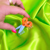 Small scissor hair claw held by a hand on a bright green background