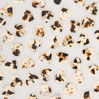 Heart-shaped buttons with a tortoiseshell pattern in cream, brown, and black, scattered on a light gray background.