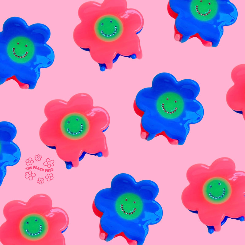 Colorful flower-shaped objects with smiley faces on a pink background