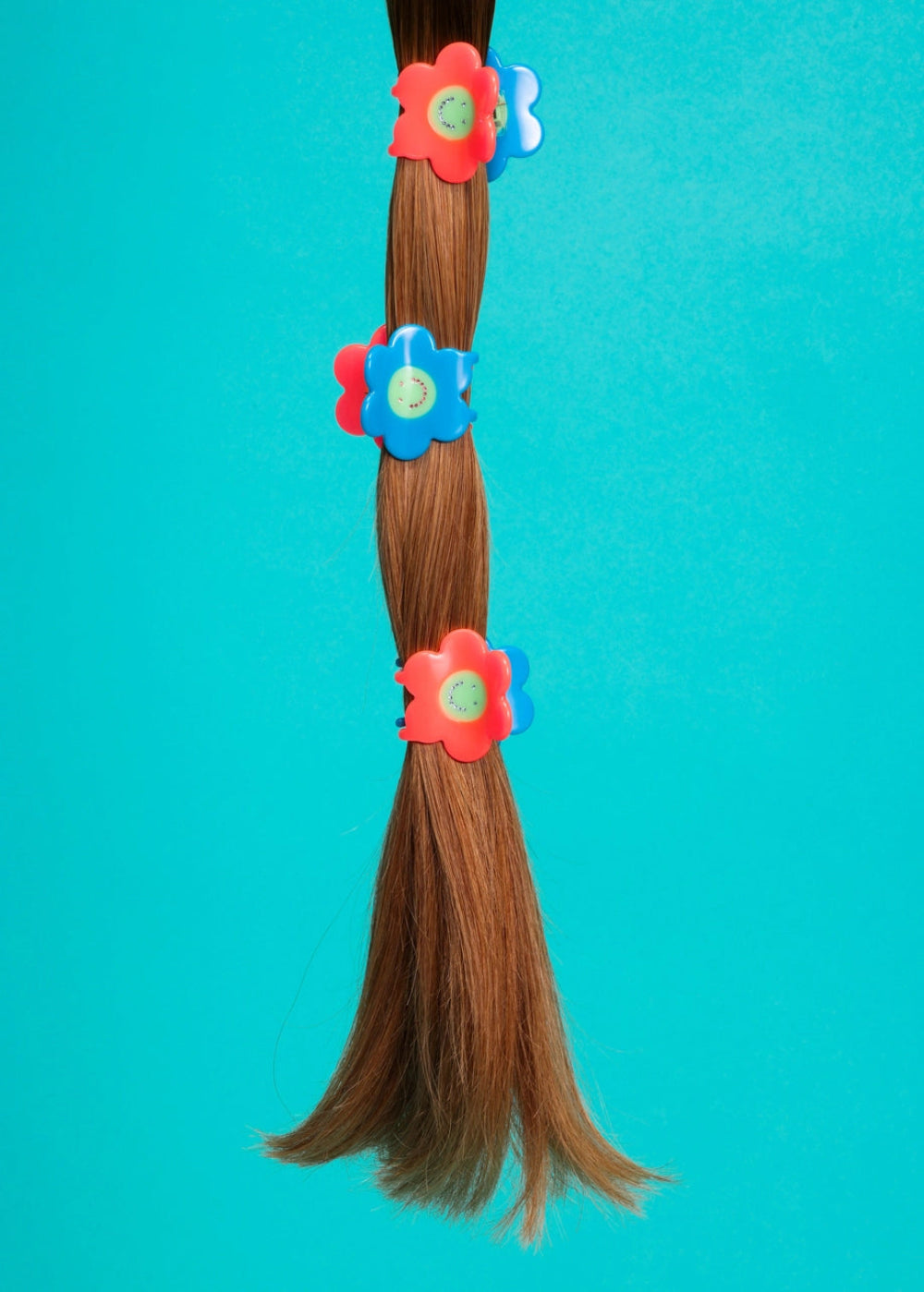 Braided hair with colorful flower clips on a turquoise background