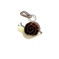 Charm in the shape of a snail attached to a gold keychain ring.