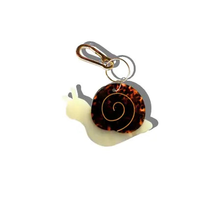 Charm in the shape of a snail attached to a gold keychain ring.