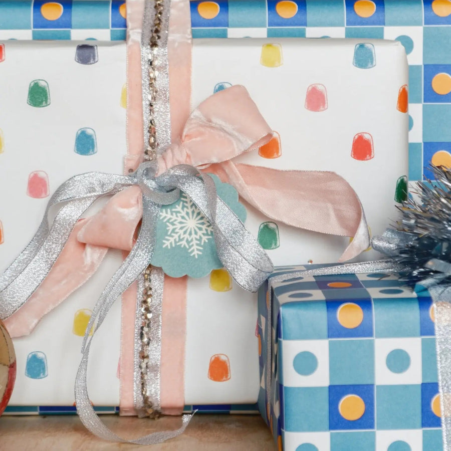 Gift wrapped in polka dot paper with ribbons and a tag on a checkered background