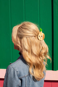 Person with blonde hair wearing an onion hair clip against a green background