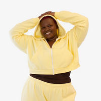A woman in a butter yellow cropped hoodie with a zipper 