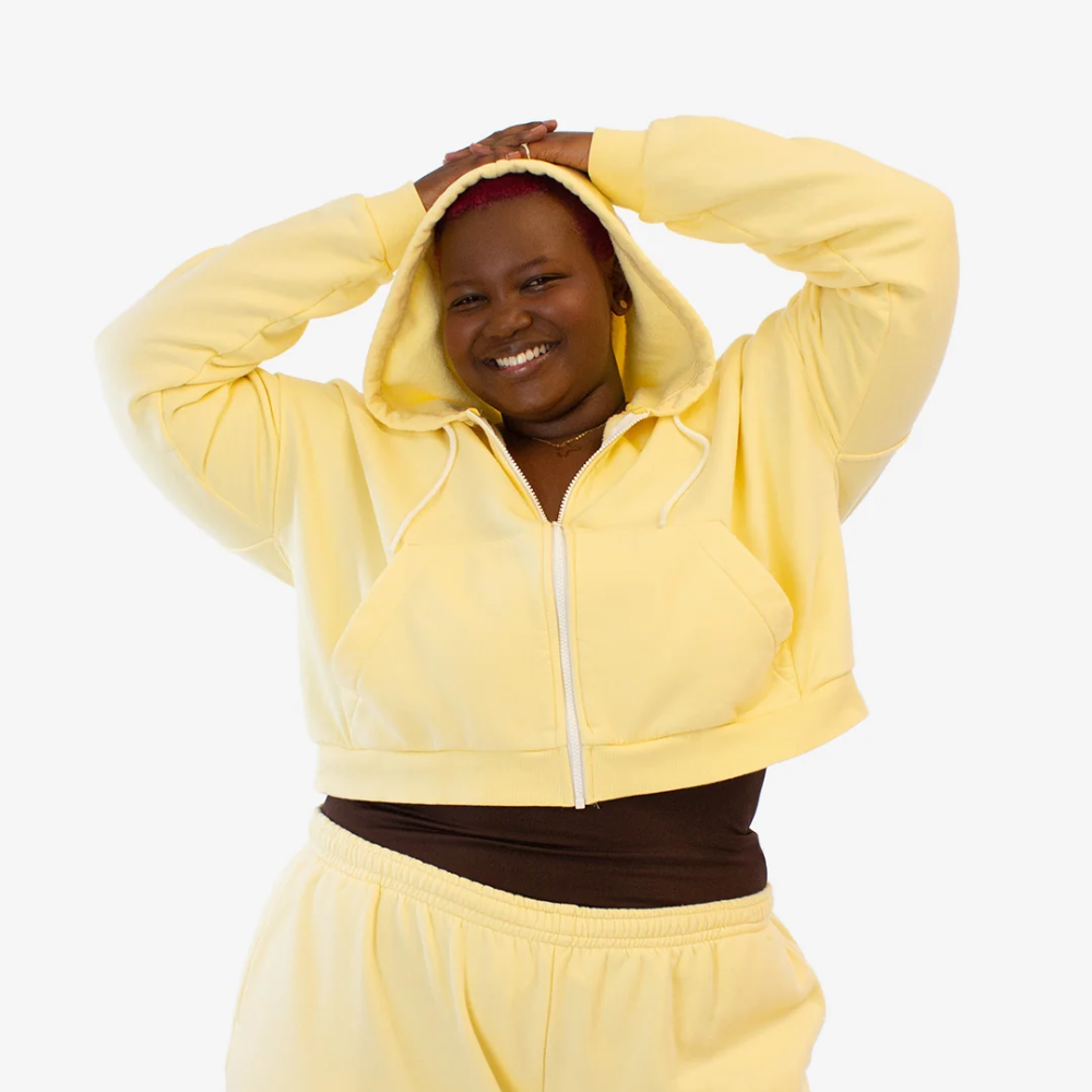 A woman in a butter yellow cropped hoodie with a zipper 
