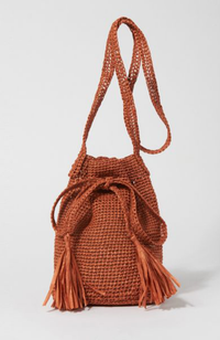 Cinnamon brown colored crocheted bucket bag with tassels, bow, and crossbody strap on a white background.