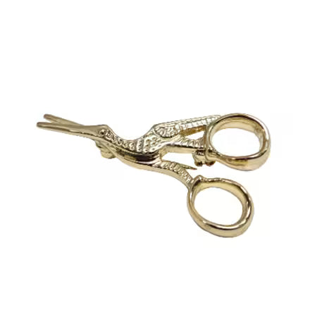 Gold stork scissors brooch on a white background