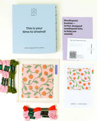 Needlepoint kit materials including canvas, thread, and instructions on a white background