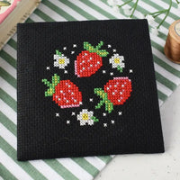 Cross-stitched strawberries and flowers on a black fabric background