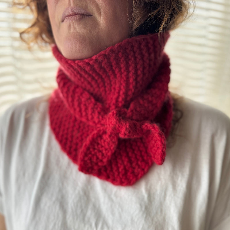 Person wearing a red knitted scarf on a white background