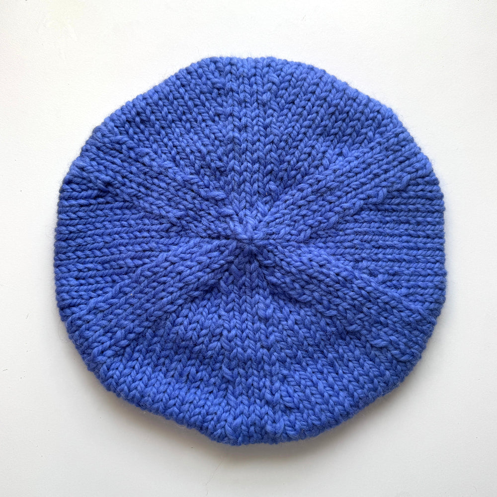 Blue knitted beret on a white background