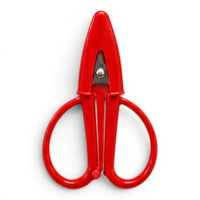 A small red pair of scissors with a matching point protector on a white background